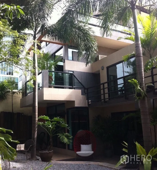 Detached House for rent in Wang Thonglang, Bangkok - Contemporary house exterior with balconies, large windows and a palm-lined courtyard.