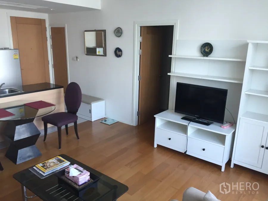 คอนโด ให้เช่าในWatthana, Bangkok - ห้องนั่งเล่นสว่างพร้อมชั้นวางทีวี ครัวแบบเปิด พื้นไม้ และโต๊ะรับประทานอาหารกระจก