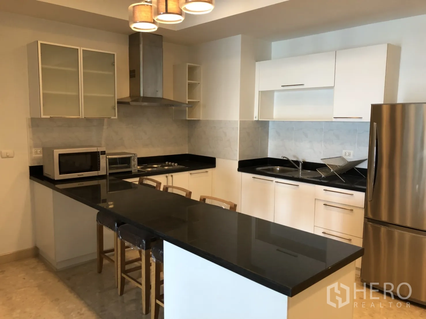คอนโด ให้เช่าในKhlong Toei, Bangkok - ครัวโมเดิร์นตู้สีขาว เคาน์เตอร์หินสีดำ พร้อมบาร์นั่งและเครื่องใช้ไฟฟ้าสแตนเลส