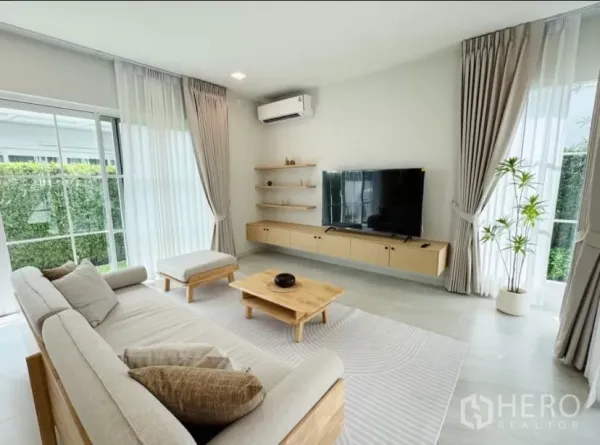 บ้าน ให้เช่าในBang Phli, Samut Prakan - ห้องนั่งเล่นสว่างด้วยโซฟารูปตัวแอล ชุดทีวี และหน้าต่างสูงจรดเพดาน