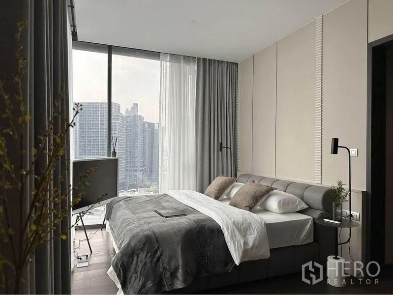 Condominium for rent or sale in Watthana, Bangkok - Primary bedroom with floor-to-ceiling corner windows and city skyline view.