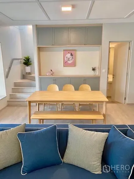 联排别墅 出租在Prawet, Bangkok - 餐区配木质餐桌与嵌入式柜体，旁有楼梯