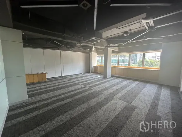 Office Space for rent in Khlong Toei, Bangkok - Corner office area with large windows, city and greenery views, and exposed ducting.