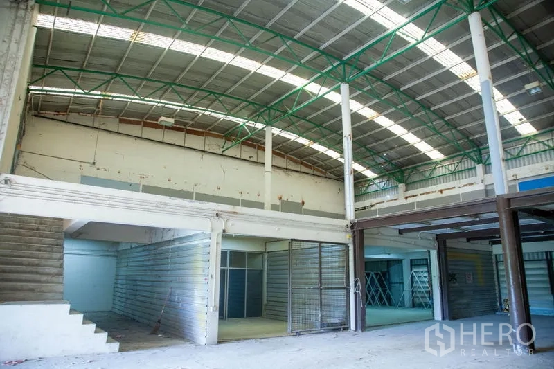 货栈 出租在Prawet, Bangkok - 宽敞仓库大厅，拱形高屋顶、绿色钢桁架与夹层储区。