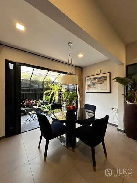Townhouse for rent or sale in Bang Phli, Samut Prakan - Bright dining area with round glass table opening to a covered patio filled with plants.