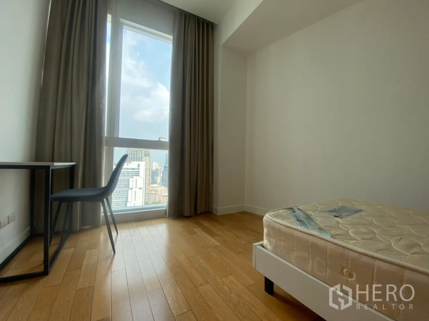 คอนโด ให้เช่าหรือขายในKhlong Toei, Bangkok - มุมห้องนอนที่สอง พร้อมโต๊ะทำงานข้างหน้าต่างสูง ผ้าม่าน และวิวสกายไลน์