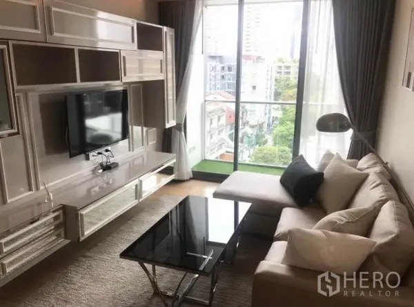 คอนโด ให้เช่าในWatthana, Bangkok - ห้องนั่งเล่นสว่าง พร้อมชั้นวางทีวีบิวท์อิน โซฟาเข้ามุม โต๊ะกลางกระจก และหน้าต่างเต็มบานเปิดสู่ระเบียงวิวเมือง