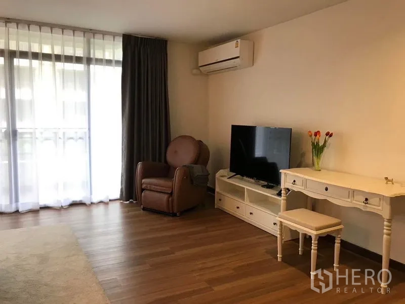 Townhouse for sale in Suan Luang, Bangkok - Bedroom sitting area with TV console, armchair and air conditioning.