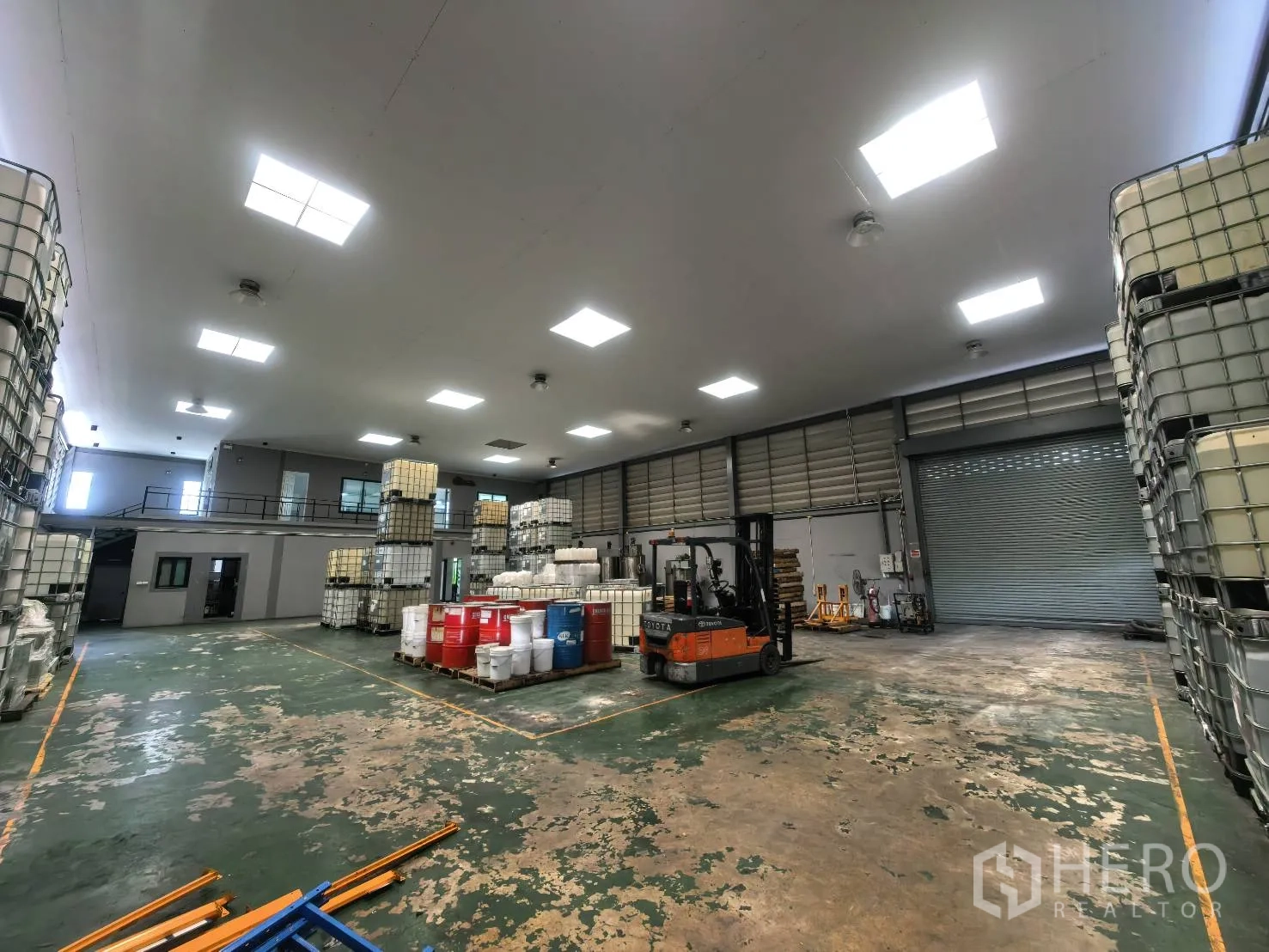 Warehouse for rent in Bang Sao Thong, Samut Prakan - Warehouse floor with a forklift, roller shutter, and storage containers.