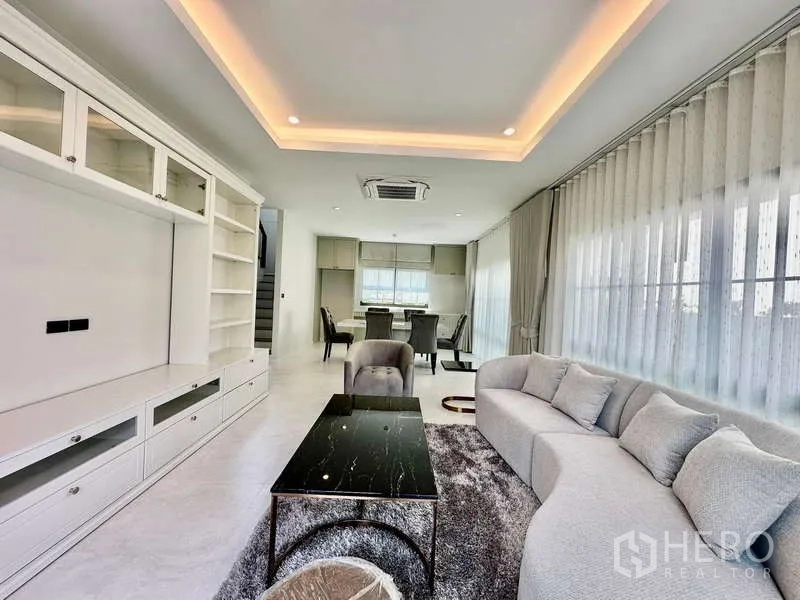 独立式住宅 出租在Bang Phli, Samut Prakan - 客厅设内置书柜、灯槽天花与弧形沙发。