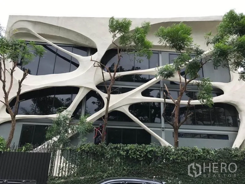 Office Space for rent in Khlong Toei, Bangkok - Front facade of contemporary office building with organic concrete design.