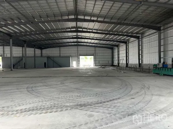 工厂 出租在Rayong - 大型厂房大厅，光滑混凝土地面，后部卷帘门与内部办公区。