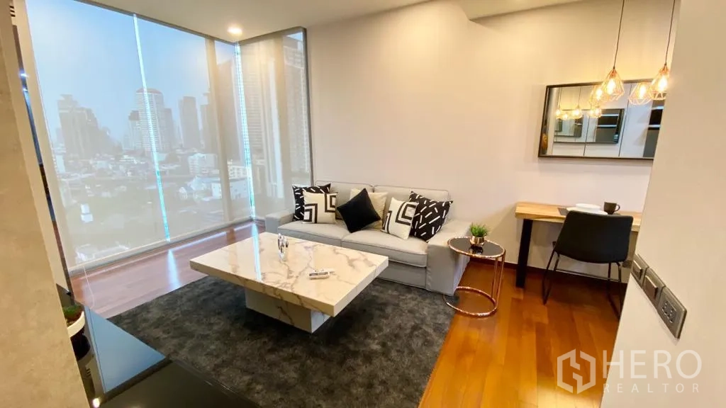 公寓 出售在Khlong Toei, Bangkok - 舒适客厅，沙发与观景窗，紧凑的餐/工作桌。