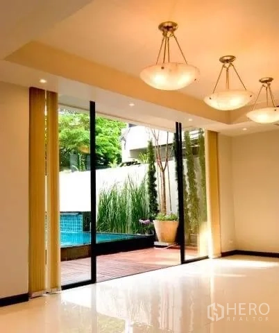 Detached House for rent in Khlong Toei, Bangkok - Bright living room with sliding glass doors opening to the deck and pool.