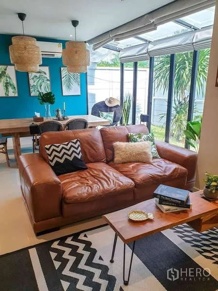 Detached House for sale in Bang Phli, Samut Prakan - Living area with brown leather sofa, full-height glass and garden view
