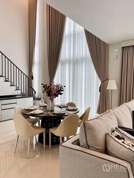 Detached House for rent or sale in Bang Kapi, Bangkok - Double-height living and dining space with tall windows and staircase.
