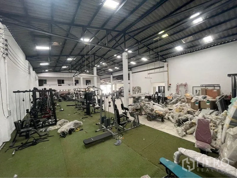 คลังสินค้า ขายในLam Luk Ka, Pathum Thani - โซนภายในแสดงอุปกรณ์ฟิตเนสวางเก็บบนพื้นหญ้าเทียม ใต้ไฟไฮเบย์