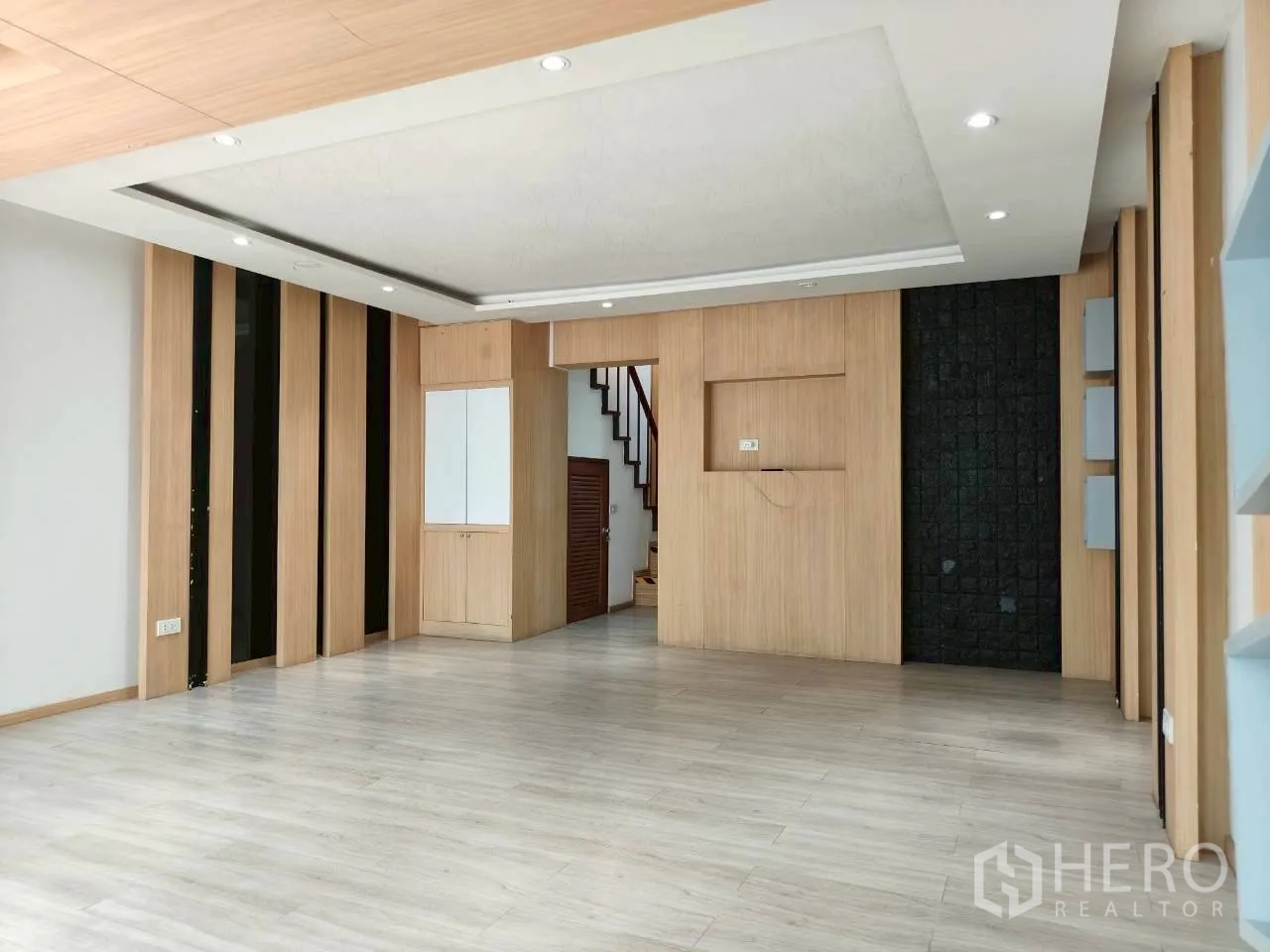 Home Office for rent in Watthana, Bangkok - Spacious open-plan room with wood paneling, recessed lights, and staircase entry.