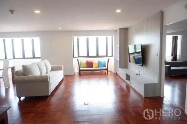 公寓 出租在Khlong Toei, Bangkok - 公寓客厅，木地板、白色沙发、电视墙与采光良好的飘窗座位