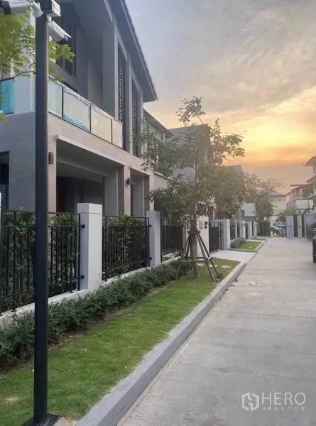 Detached House for rent in Lak Si, Bangkok - Tree-lined residential street with contemporary homes, front fences and sunset sky.