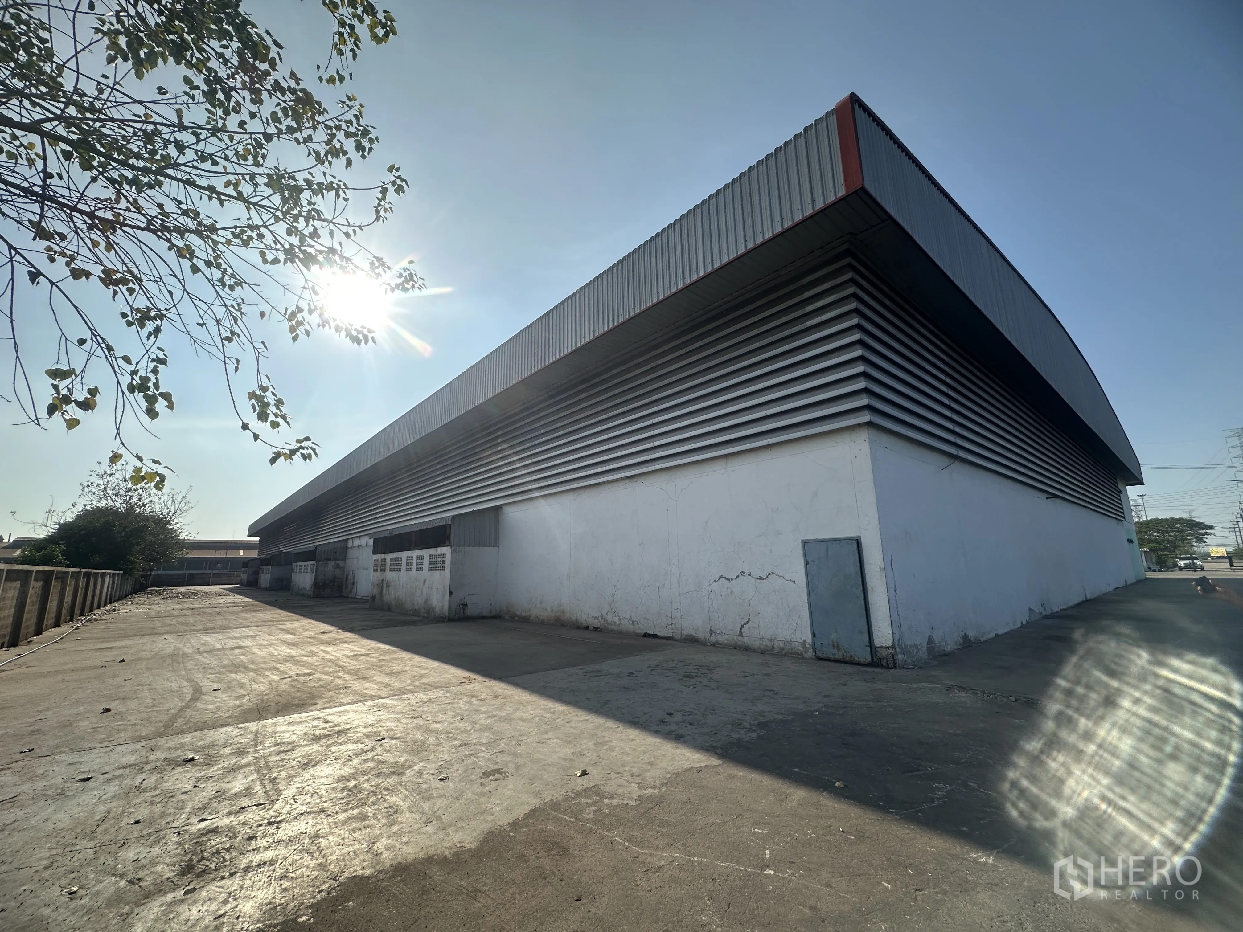 Factory for rent in Wang Noi, Phra Nakhon Si Ayutthaya - Side elevation of the warehouse with ribbed metal cladding and an open service yard under a bright sky.