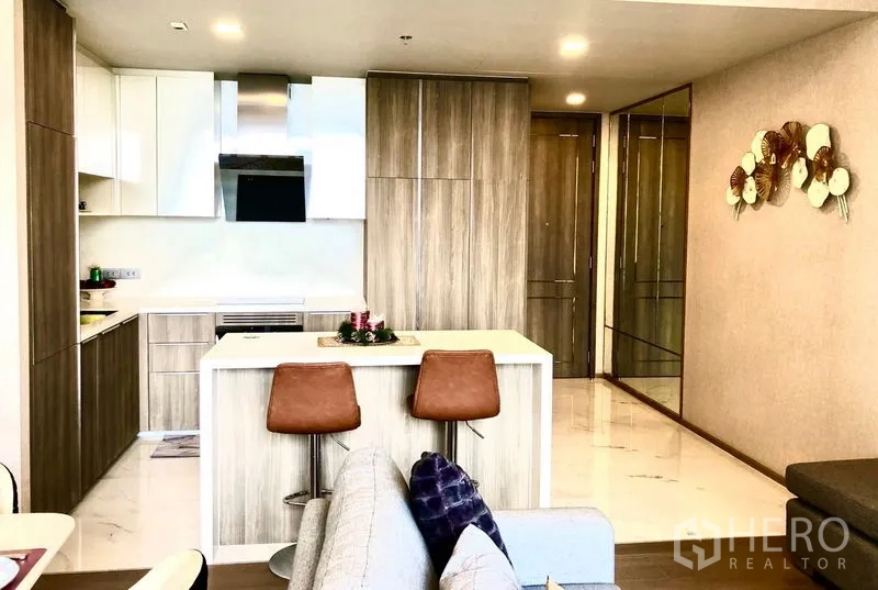 Condominium for rent in Watthana, Bangkok - Modern kitchen with island breakfast bar, wood cabinetry and integrated appliances.