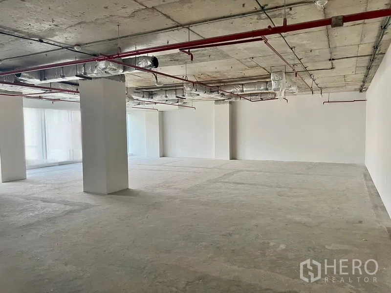 Office Space for rent in Sathon, Bangkok - Open-plan shell-and-core office floor with exposed ceiling ducts, red sprinkler pipes, concrete floor, and white columns in Sathon, Bangkok.