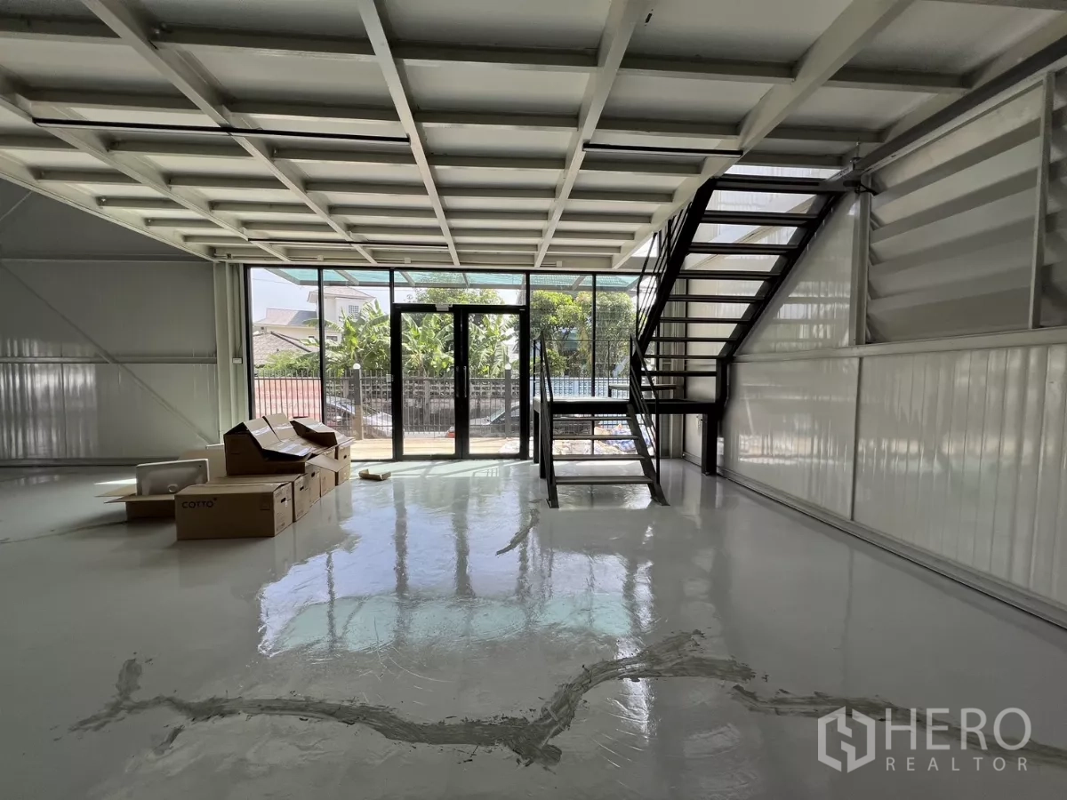 Warehouse for rent in Bang Na, Bangkok - Entrance area with double glass doors, staircase to mezzanine, and glossy floors.