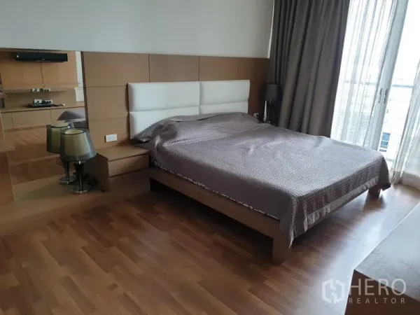 Condominium for rent in Watthana, Bangkok - Spacious master bedroom with double bed, bedside tables, wood floors and balcony access through sheer curtains.