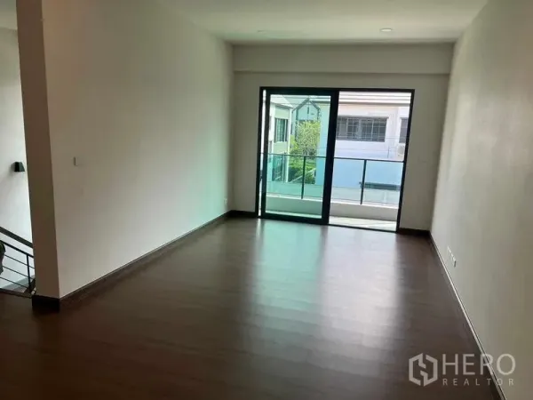 Detached House for rent in Khlong Sam Wa, Bangkok - Bright room with sliding glass doors opening to a balcony and wood floors.