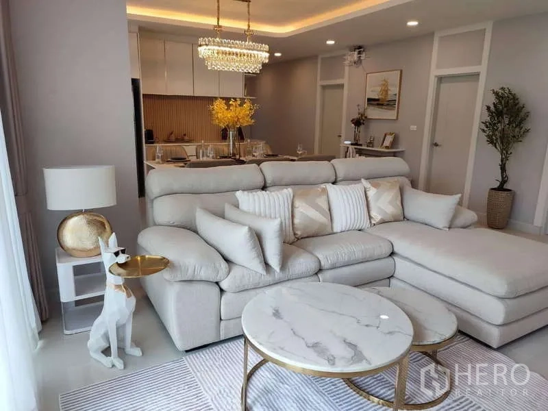 Detached House for rent in Bang Phli, Samut Prakan - Open-plan living and dining with L-shaped sofa, marble coffee tables and chandelier.