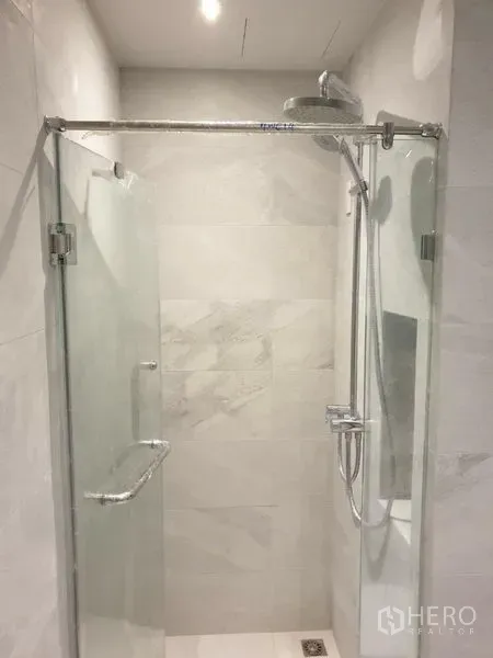 Condominium for sale in Watthana, Bangkok - Bright modern bathroom featuring a glass shower enclosure and rain shower head.