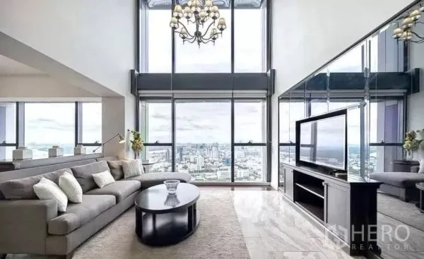 Condominium for rent in Sathon, Bangkok - Double-height living room at The Met Sathorn with floor-to-ceiling windows, chandelier, sectional sofa and skyline view.