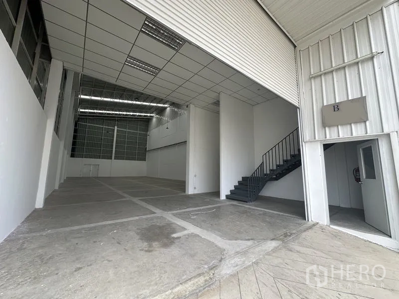 工厂 出租在Khlong Luang, Pathum Thani - 厂房入口，设高卷闸门、夹层办公室与钢制楼梯。