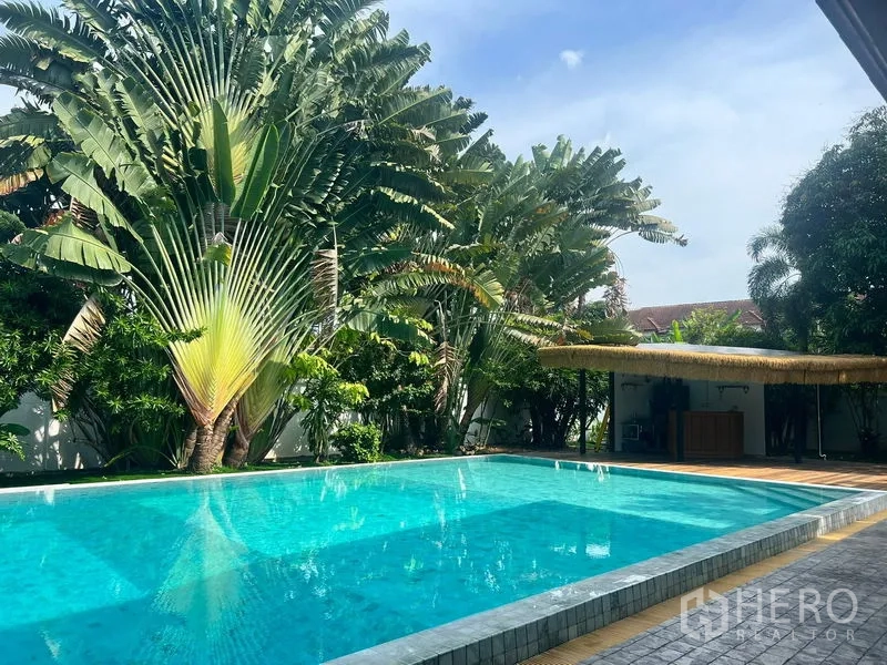Detached House for sale in Prawet, Bangkok - Resort-style private swimming pool surrounded by lush tropical palms and a shady cabana.