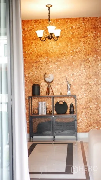 Detached House for rent or sale in Bang Bo, Samut Prakan - Accent wall with warm textured wallpaper, metal shelf decor and chandelier in a modern hallway.
