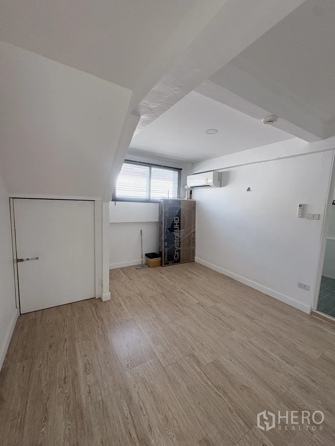 Detached House for rent in Saphan Sung, Bangkok - Small room with wood-look floor, under-stair storage door, window blinds, and wall air conditioner.
