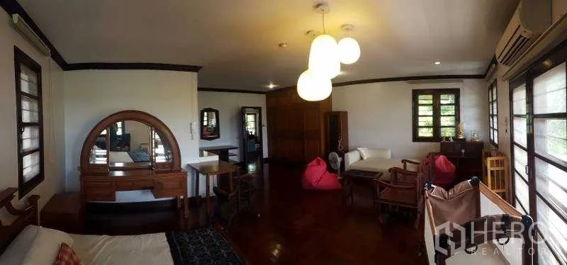 Detached House for rent in Bang Phli, Samut Prakan - Large bedroom with polished wood floors, vanity and seating corner.
