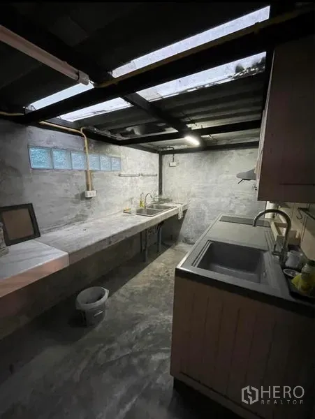 Shophouse for rent in Chatuchak, Bangkok - Back kitchen with concrete countertops, twin sinks and a skylight roof.
