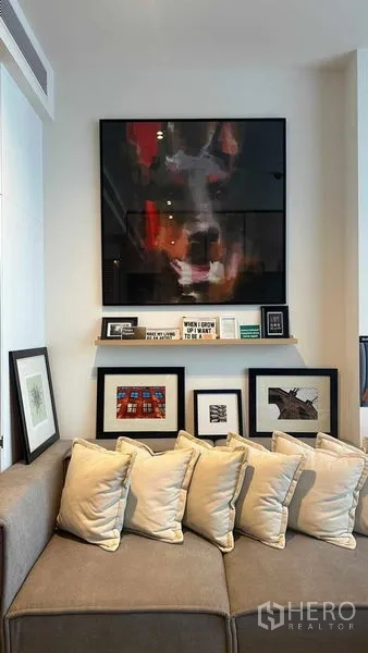 Condominium for sale - Art display shelves and framed pictures above a corner sofa in the unit.