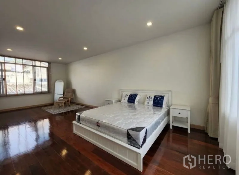 Townhouse for sale - Expansive bedroom layout with king bed, seating corner and glossy wooden floors.