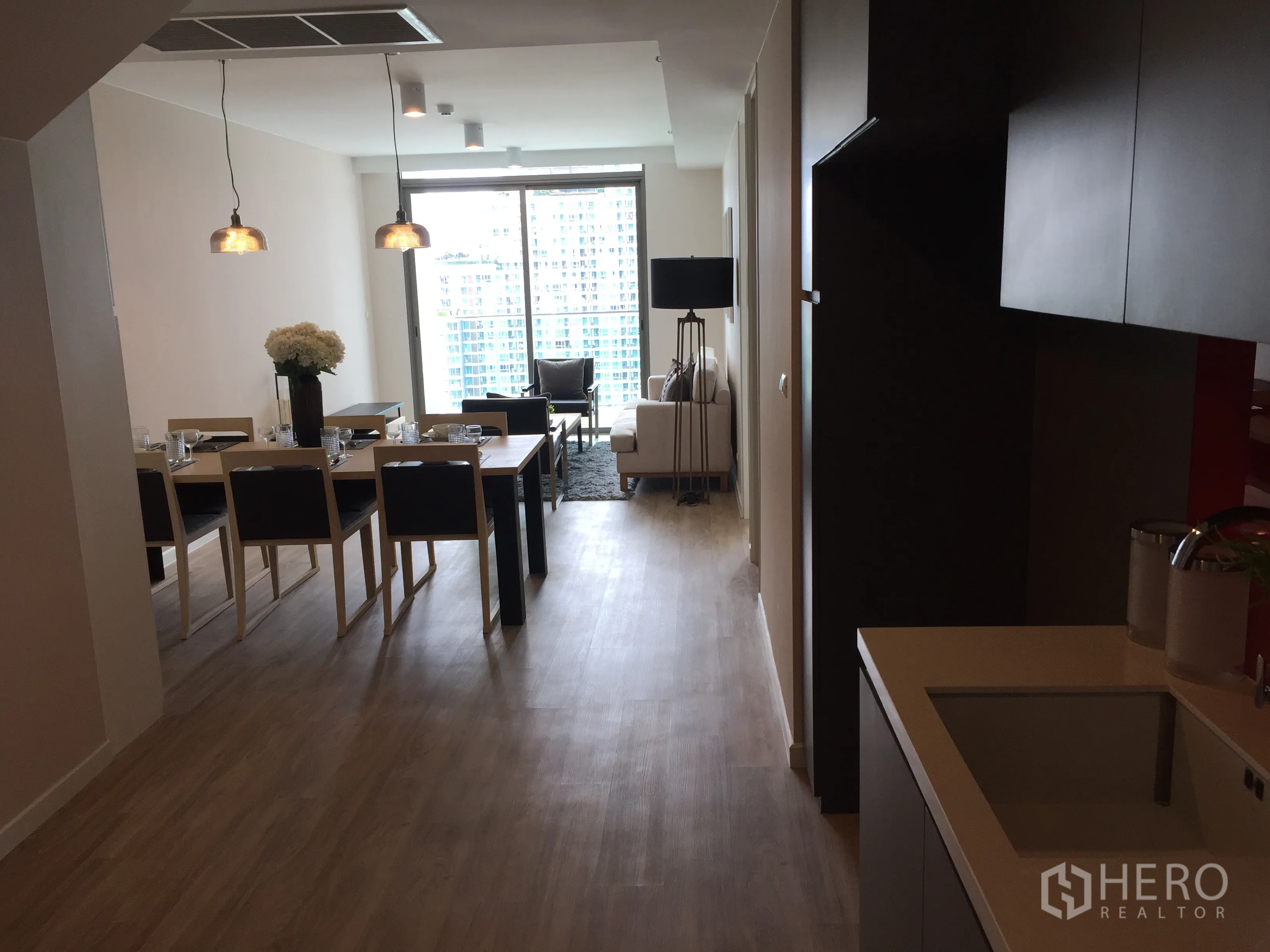 公寓 出售在Bang Rak, Bangkok - 开放式厨房、餐桌与客厅，落地窗引入城市景观。