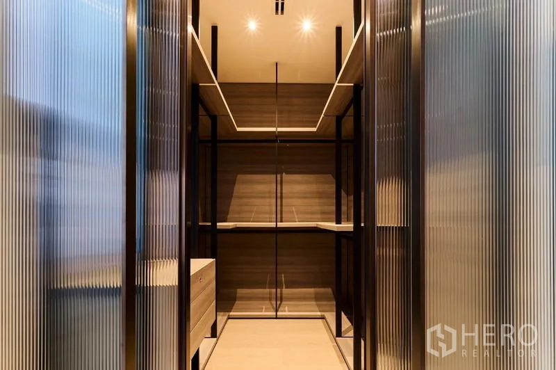 Condominium for rent in Pathum Wan, Bangkok - Walk-in closet with open shelving and metal frames behind ribbed glass doors.