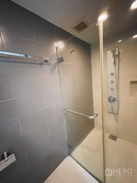 公寓 出租或出售在Khlong Toei, Bangkok - 玻璃淋浴间，顶喷花洒与灰色墙砖。