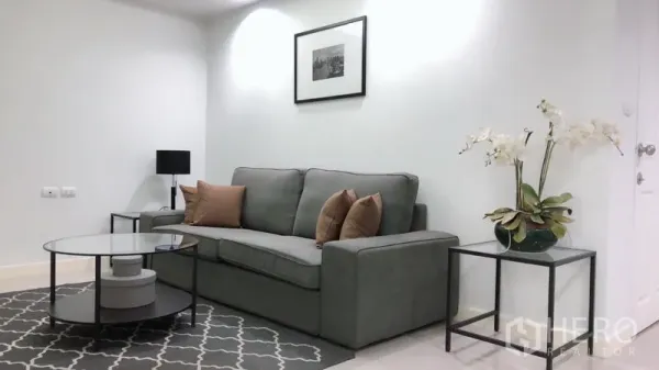 คอนโด ให้เช่าหรือขายในKhlong Toei, Bangkok - ห้องนั่งเล่นสว่าง โซฟาสีเทา โต๊ะกลางกระจก กรอบรูป และแจกันกล้วยไม้