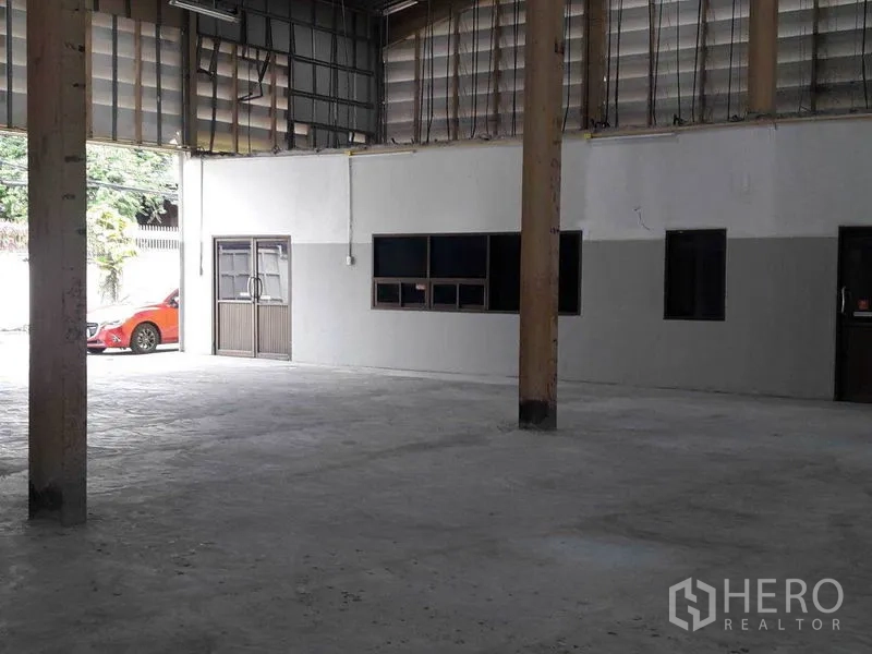 Warehouse for rent in Bang Sue, Bangkok - Spacious warehouse interior with high ceiling, concrete floor, office windows, and wide entry in Bang Sue, Bangkok.