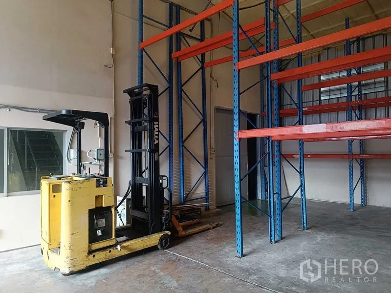 Warehouse for rent in Suan Luang, Bangkok - Yellow electric reach truck parked beside racking in the loading zone.