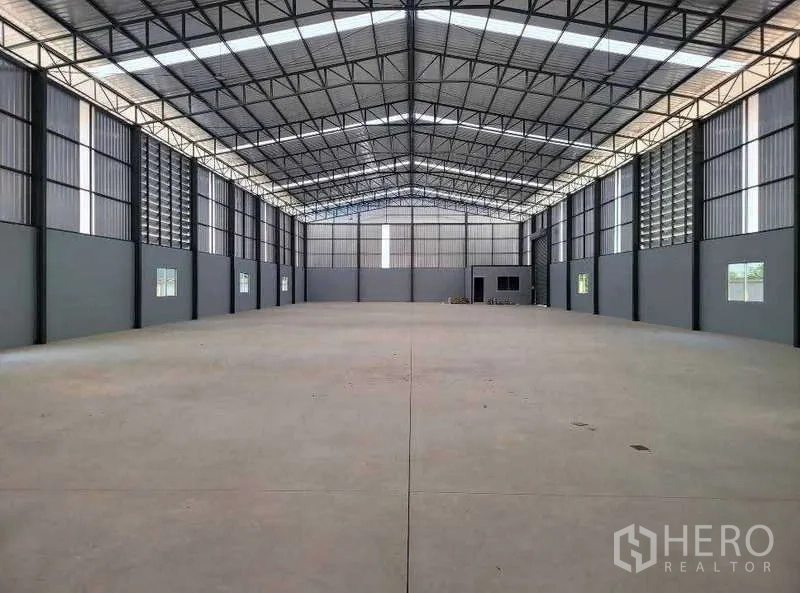 Warehouse for sale in Ban Bueng, Chon Buri - Spacious high-ceiling steel-frame warehouse interior with polished concrete floor and side windows in Ban Bueng, Chon Buri.