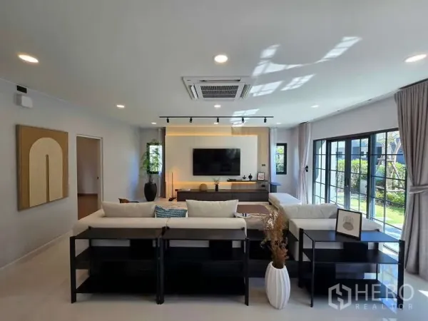 Detached House for rent in Bang Phli, Samut Prakan - Living area with feature TV wall, floor-to-ceiling windows and garden view.