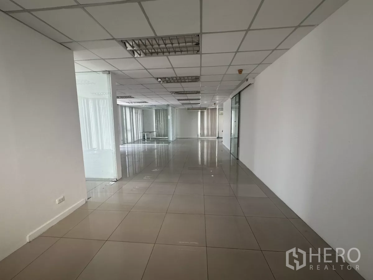 Office Space for rent in Huai Khwang, Bangkok - Empty open office area with windows, glass partitions and light tile flooring.